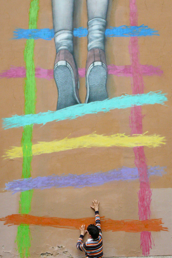 bambino che sale una scala disegnata su un muro. foto di Laura Marzano del laboratorio di fotografia della fondazione Di Liegro